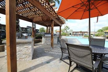 A patio with a table and chairs under an orange umbrella